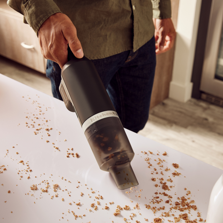 A KitchenAid Go™ Cordless Vacuum cleaning up crumbs.