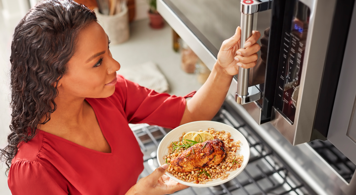 Person preparing heat up food in a KitchenAid® stainless steel microwave Person preparing heat up food in a KitchenAid® stainless steel microwave