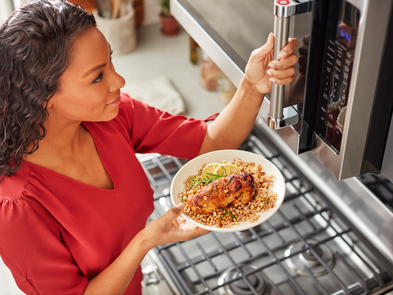 Person preparing heat up food in a KitchenAid® stainless steel microwave Person preparing heat up food in a KitchenAid® stainless steel microwave