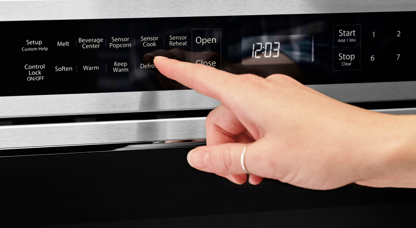 Person using the defrost option on a KitchenAid® microwave Person using the defrost option on a KitchenAid® microwave