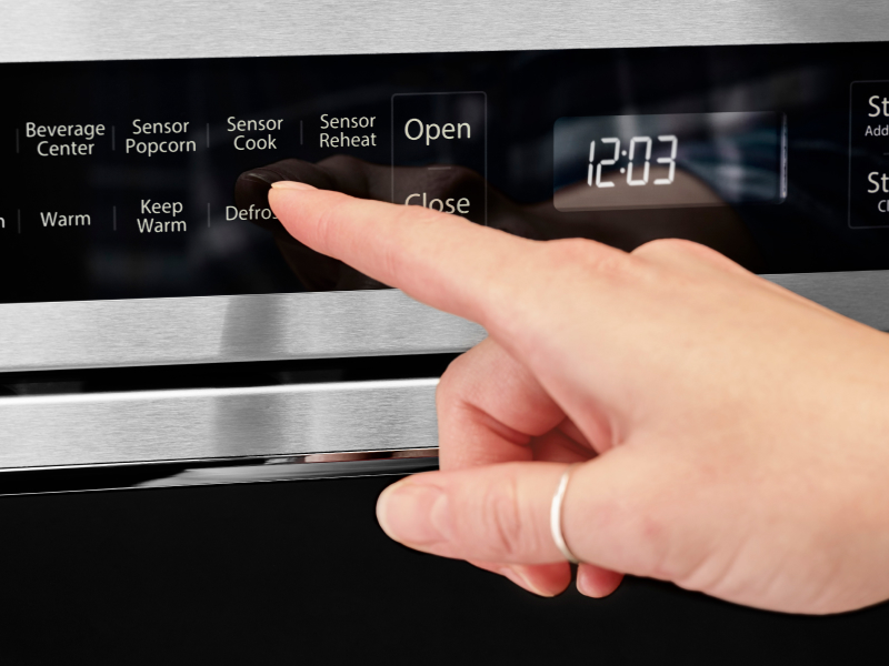 Person using the defrost option on a KitchenAid® microwave Person using the defrost option on a KitchenAid® microwave
