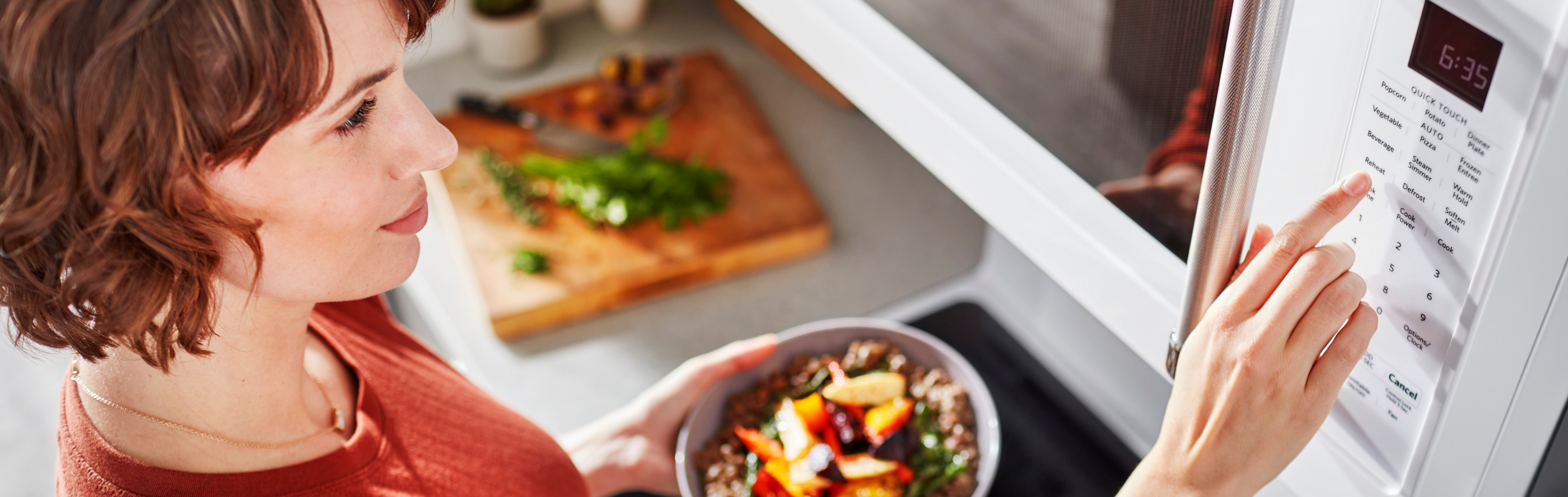 Person pushing buttons on a microwave control panel