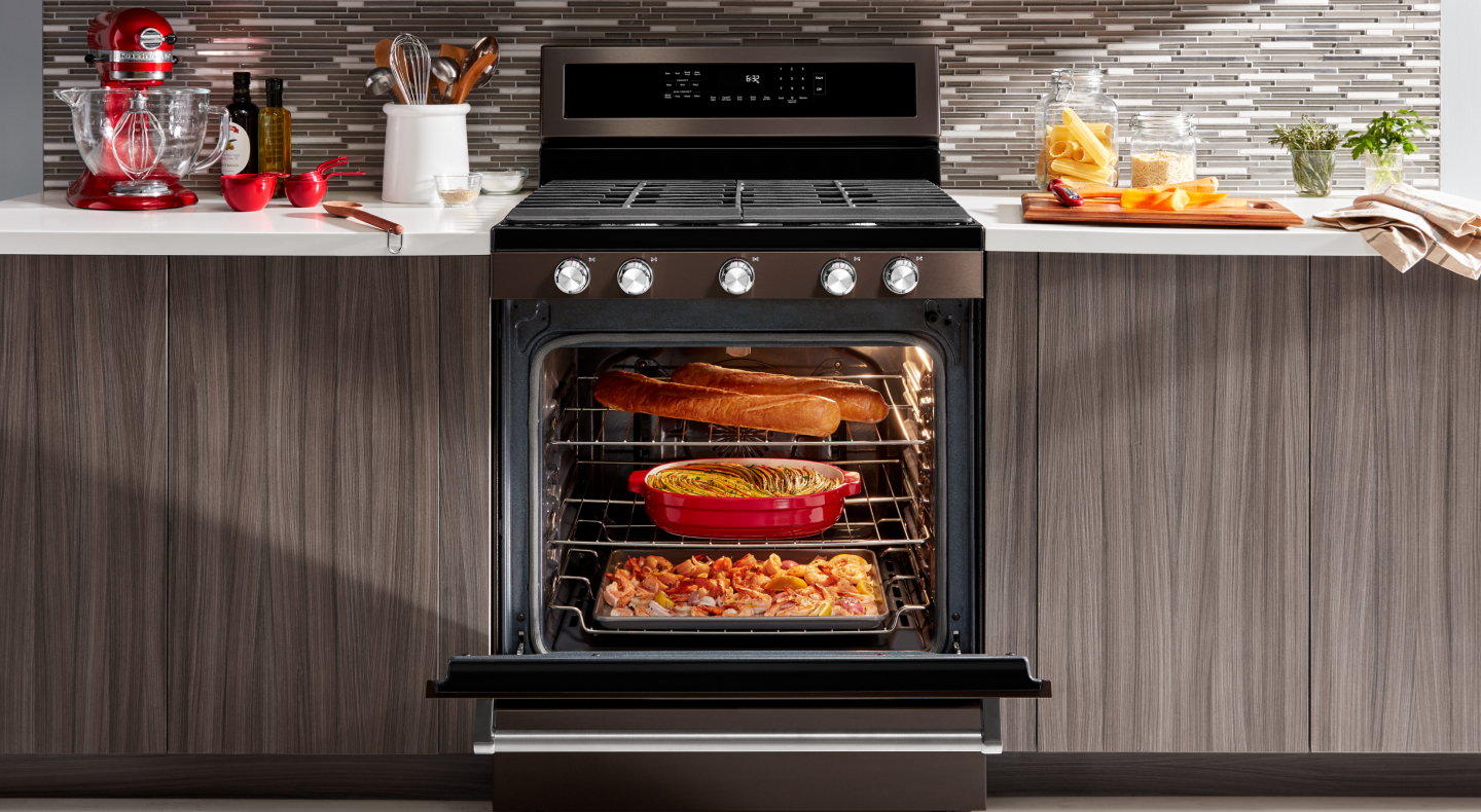 A slide-in range with three different dishes cooking inside