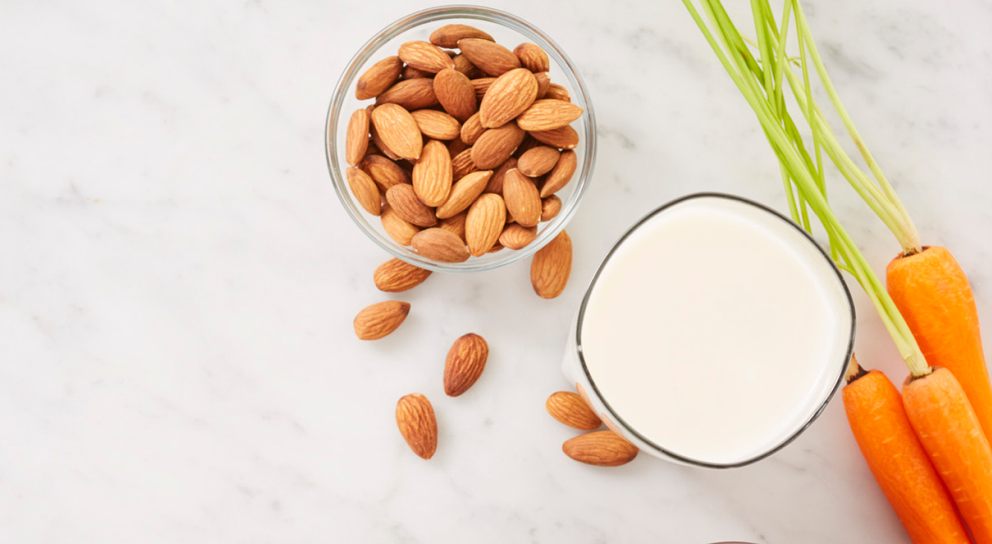 A bowl of almonds and a glass of almond milk