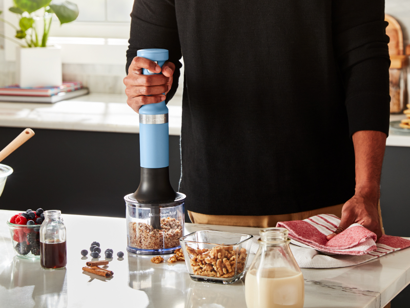 A person using a KitchenAid® immersion blender to process nuts A person using a KitchenAid® immersion blender to process nuts