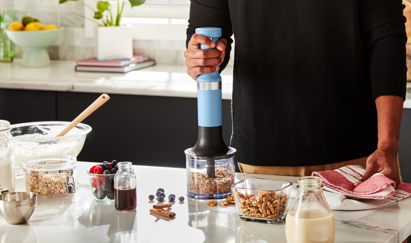 A person using a KitchenAid® immersion blender to process nuts A person using a KitchenAid® immersion blender to process nuts