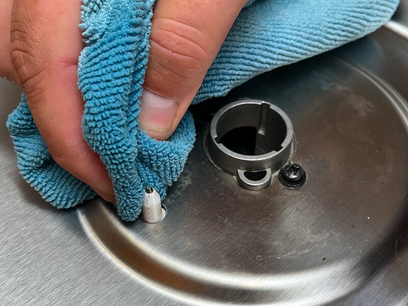 A hand shown cleaning debris from the igniter with a damp cloth