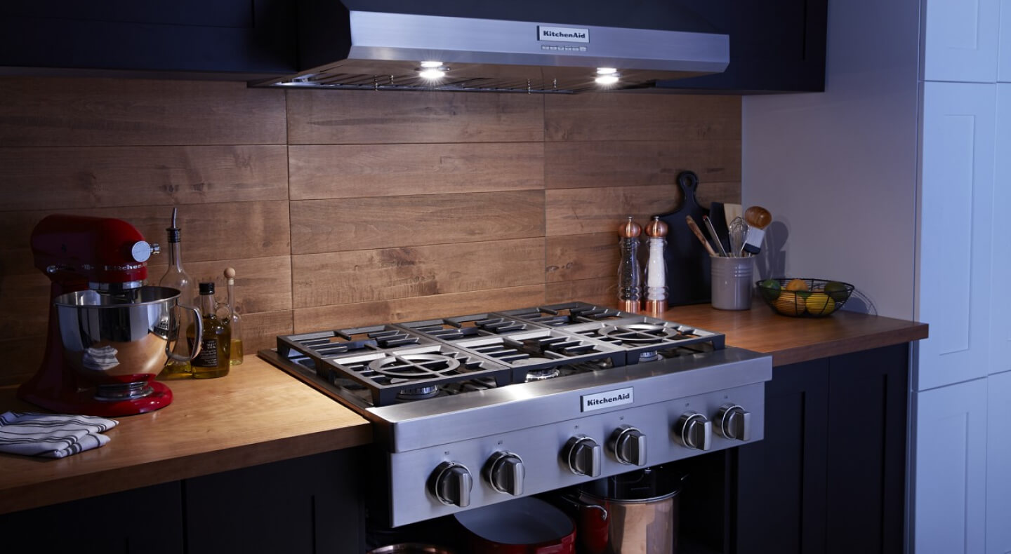 A kitchen with wood countertops and detailing and a gas range