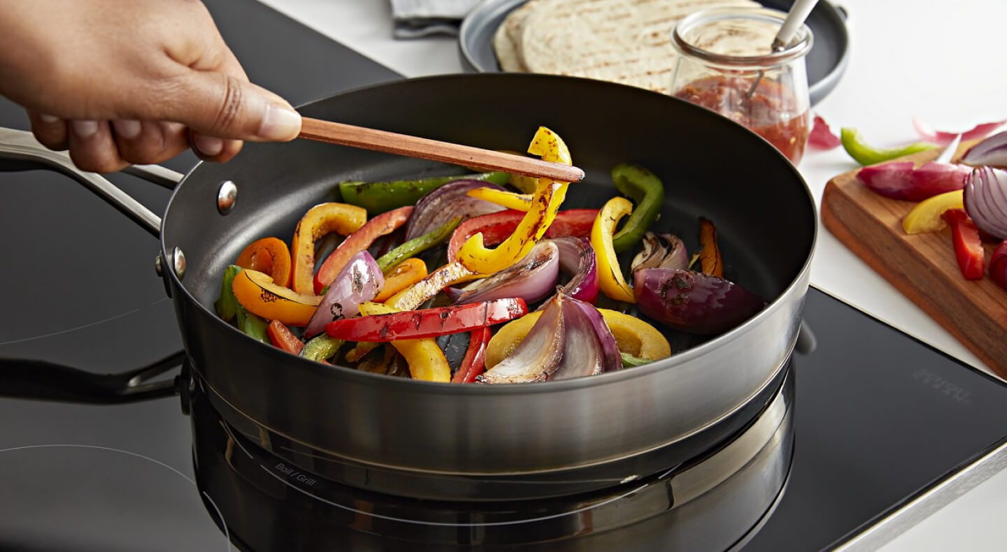 Person cooking vegetables on a stovetop Person cooking vegetables on a stovetop
