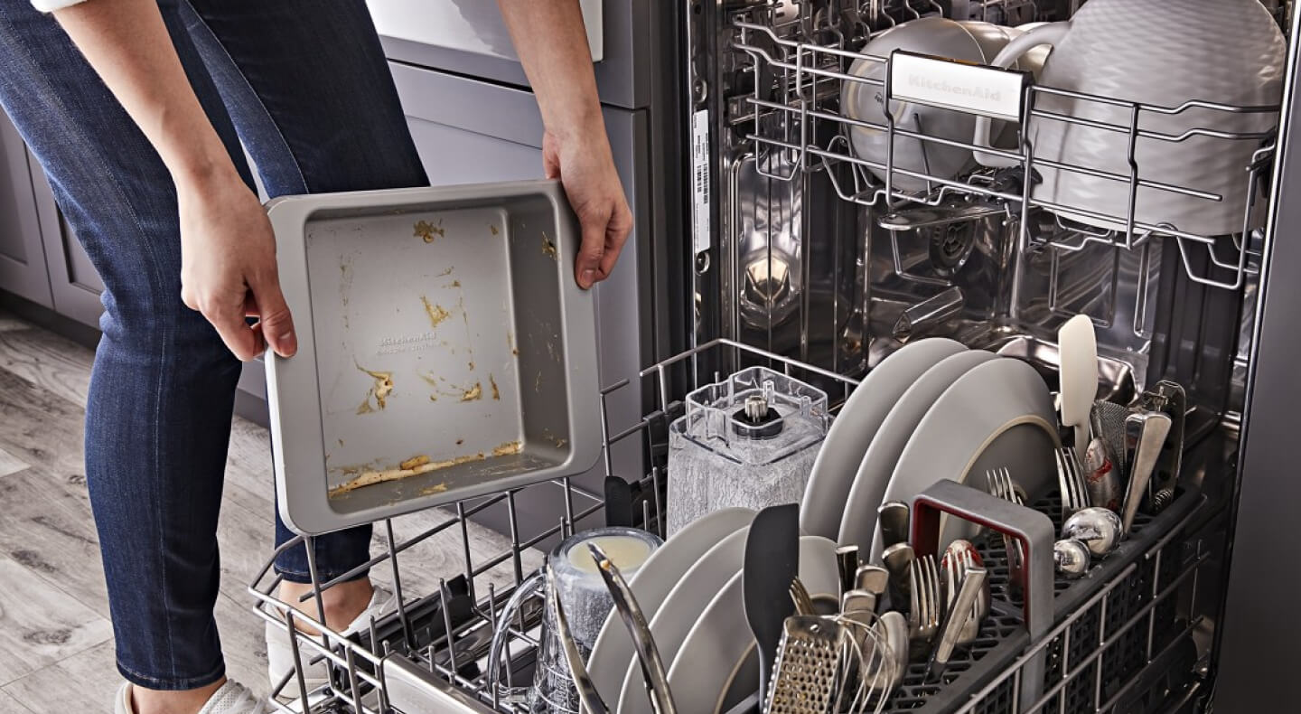 Person loading dirty dishes into a dishwasher Person loading dirty dishes into a dishwasher