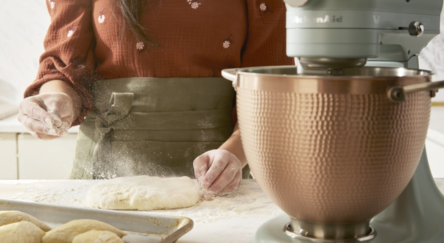 Person working with dough next to a KitchenAid® stand mixer Person working with dough next to a KitchenAid® stand mixer