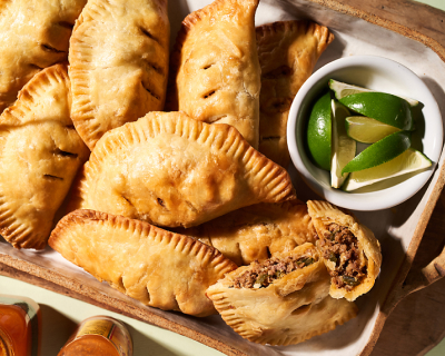 Empanadas on platter next to bowl of lime wedges Empanadas on platter next to bowl of lime wedges