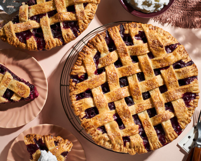 Whole blueberry lattice pie surrounded by plates with slices of blueberry pie Whole blueberry lattice pie surrounded by plates with slices of blueberry pie