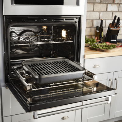An open KitchenAid® oven with a grill pan