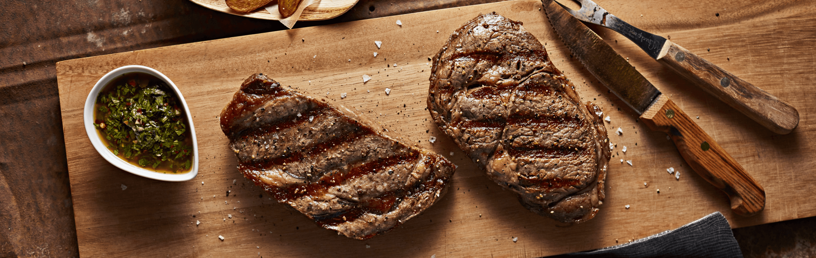 Two grilled steaks on a cutting board