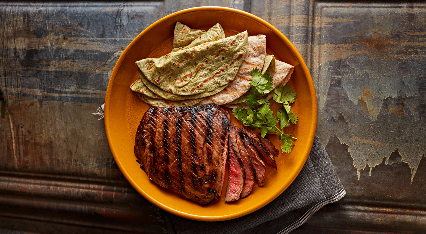 Sliced steak and fresh tortillas garnished with herbs Sliced steak and fresh tortillas garnished with herbs