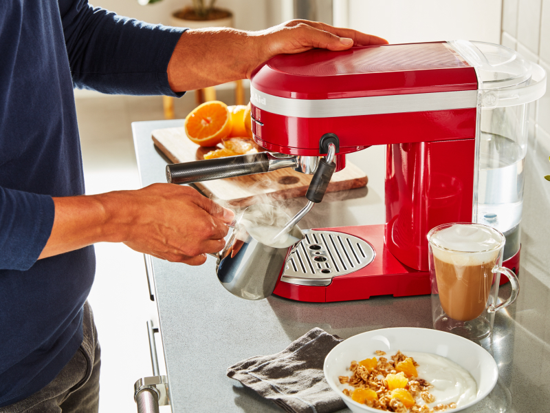Man steaming milk with the steam wand on a  KitchenAid® espresso machine