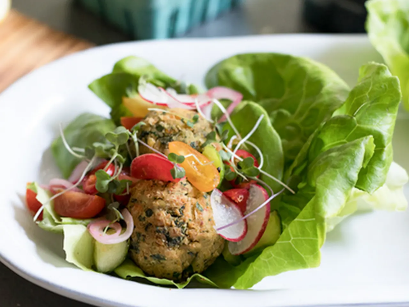 Close-up of salad with lettuce topped with radish, falafel and veggies