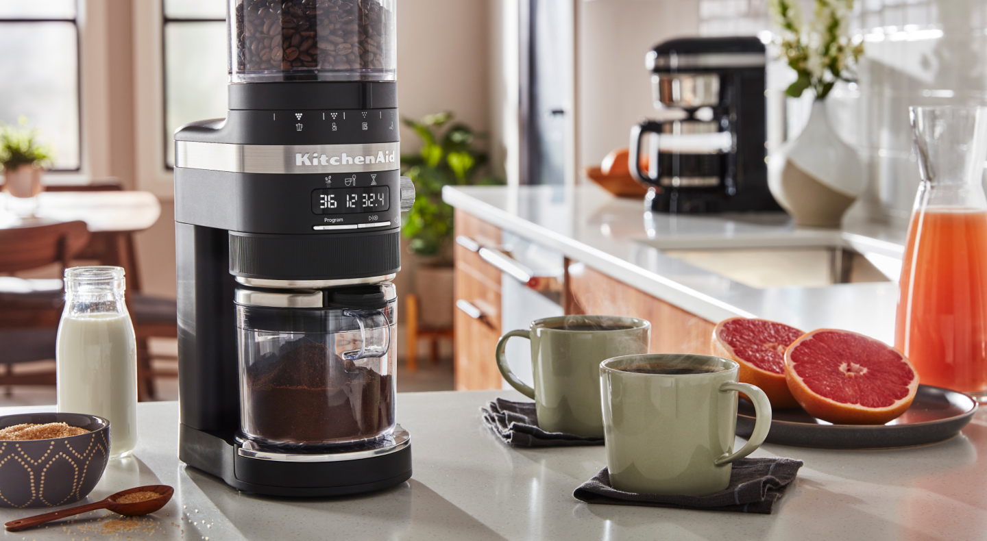 Coffee maker on counter with mugs full of coffee and halved grapefruit pieces  Coffee maker on counter with mugs full of coffee and halved grapefruit pieces