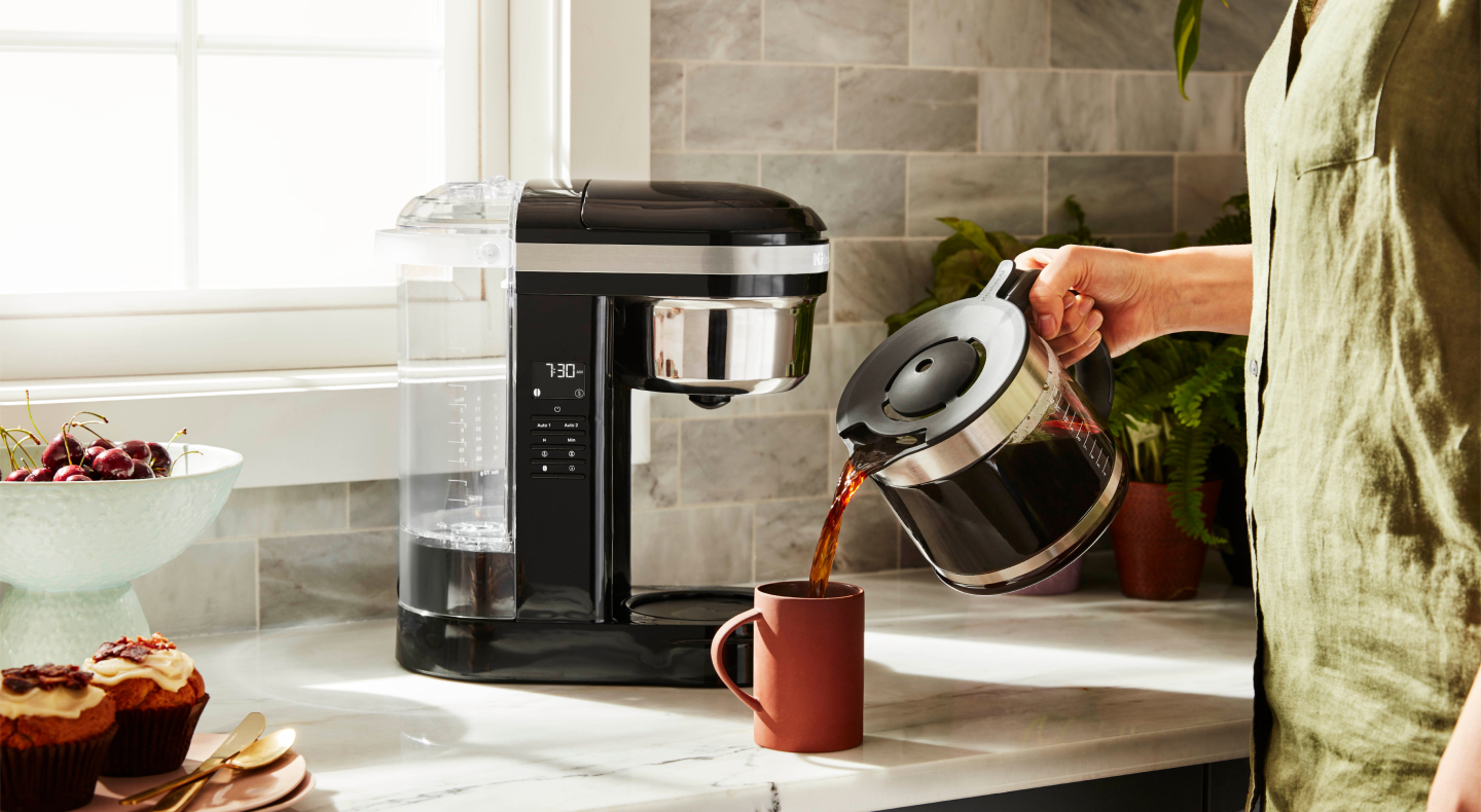 Person pouring a pitcher of coffee into a mug Person pouring a pitcher of coffee into a mug