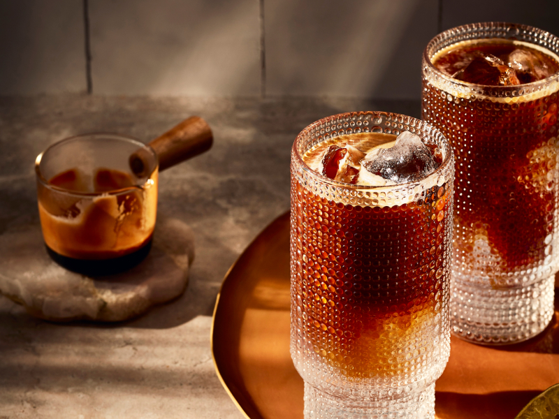Two iced espresso drinks in tall glasses