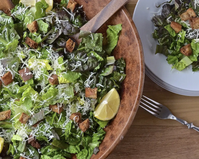 A serving bowl filled with a crisp salad topped with limes and shredded cheese.