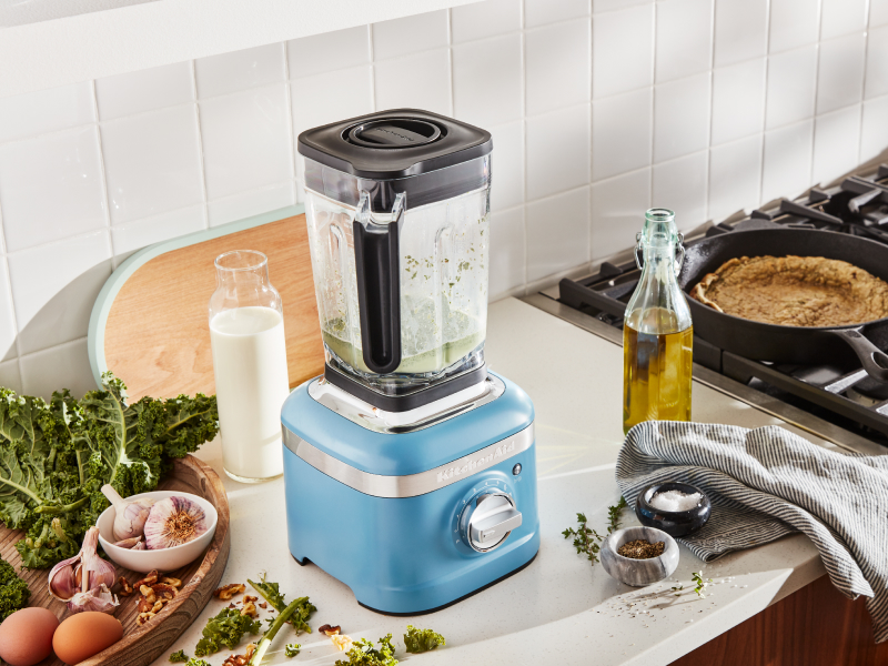 A KitchenAid® blender surrounded by various herbs and vegetable oil. A KitchenAid® blender surrounded by various herbs and vegetable oil.
