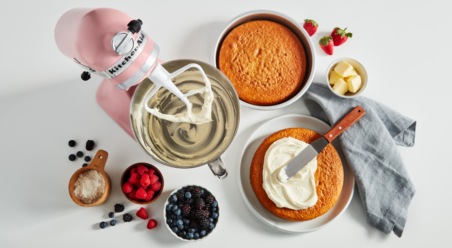Stand mixer, cake layers and ingredients on a counter Stand mixer, cake layers and ingredients on a counter