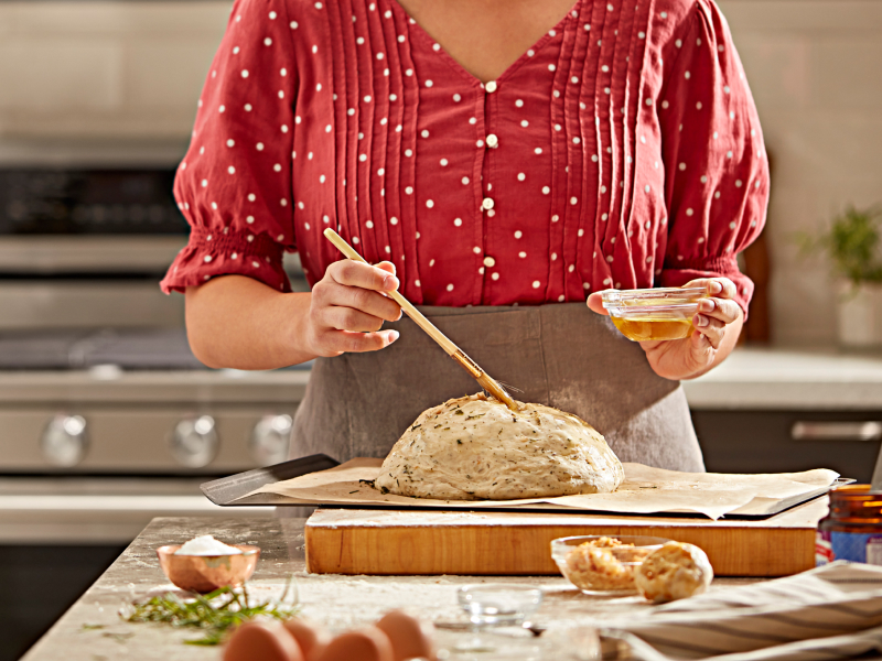 Person brushing egg on bread dough Person brushing egg on bread dough
