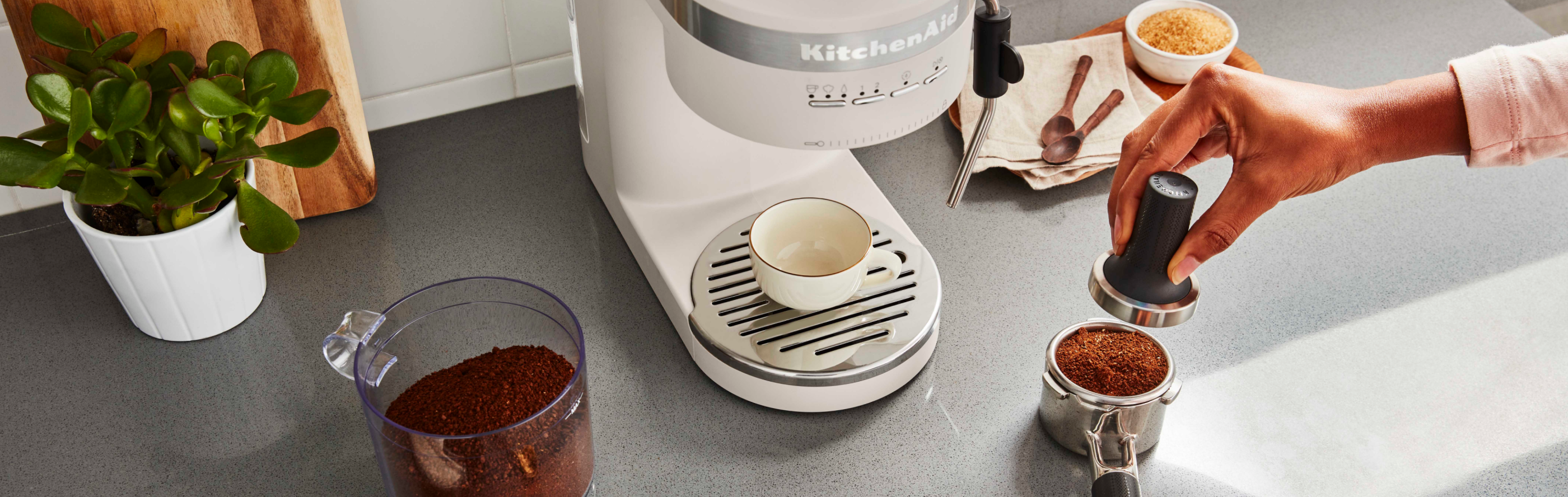 Espresso coffee being tamped in portafilter next to espresso machine