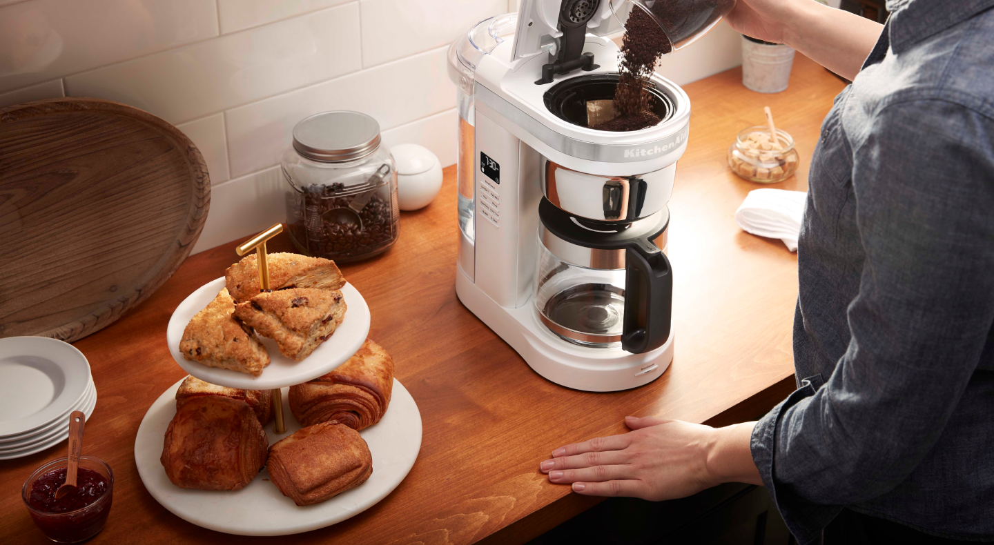 Woman pouring coffee grounds into drip coffee maker Woman pouring coffee grounds into drip coffee maker