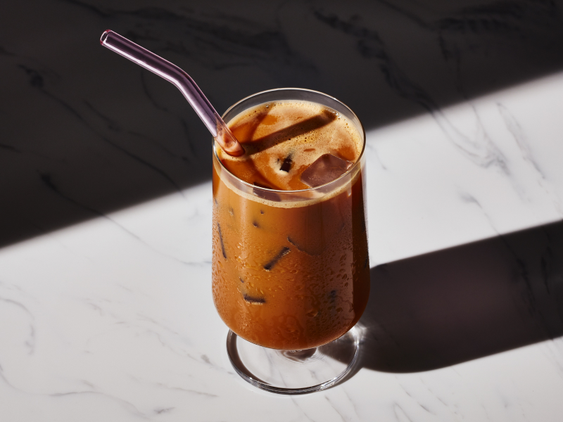 Glass of café con hielo with metal straw on granite countertop