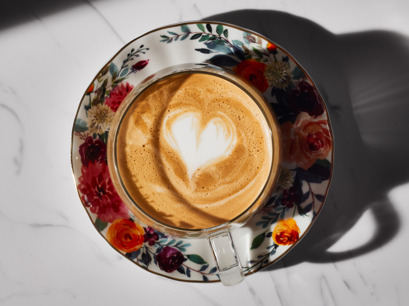 Noisette with milk foam art in teacup on ornate plate