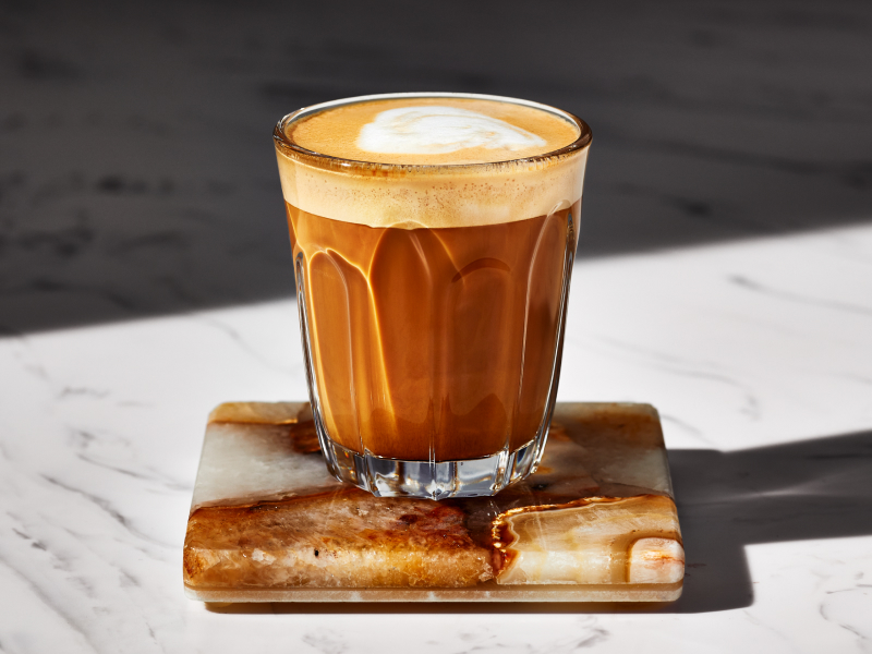 A breve in a glass cup on a dark granite coaster