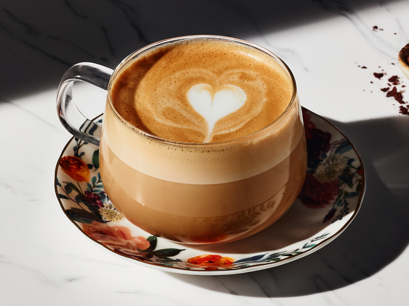 Cappuccino in glass teacup on small plate