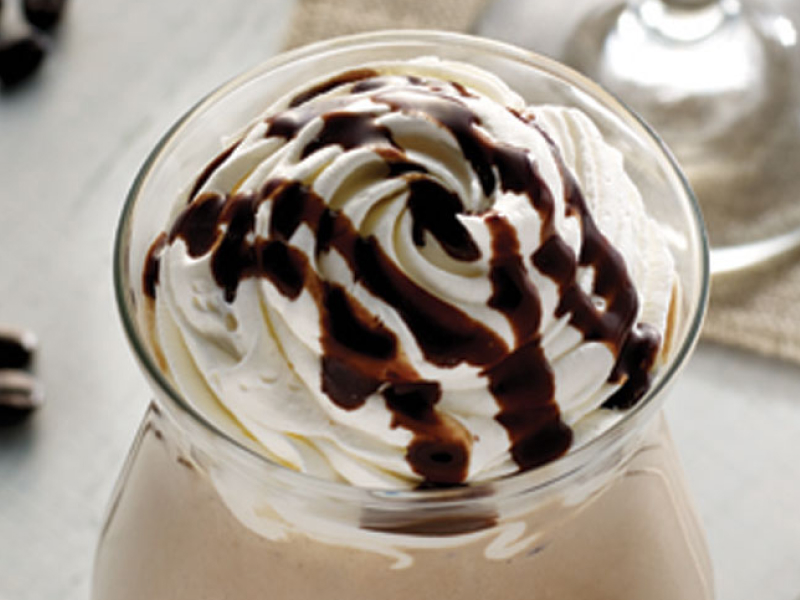 Whipped topping with chocolate drizzle in coffee cup