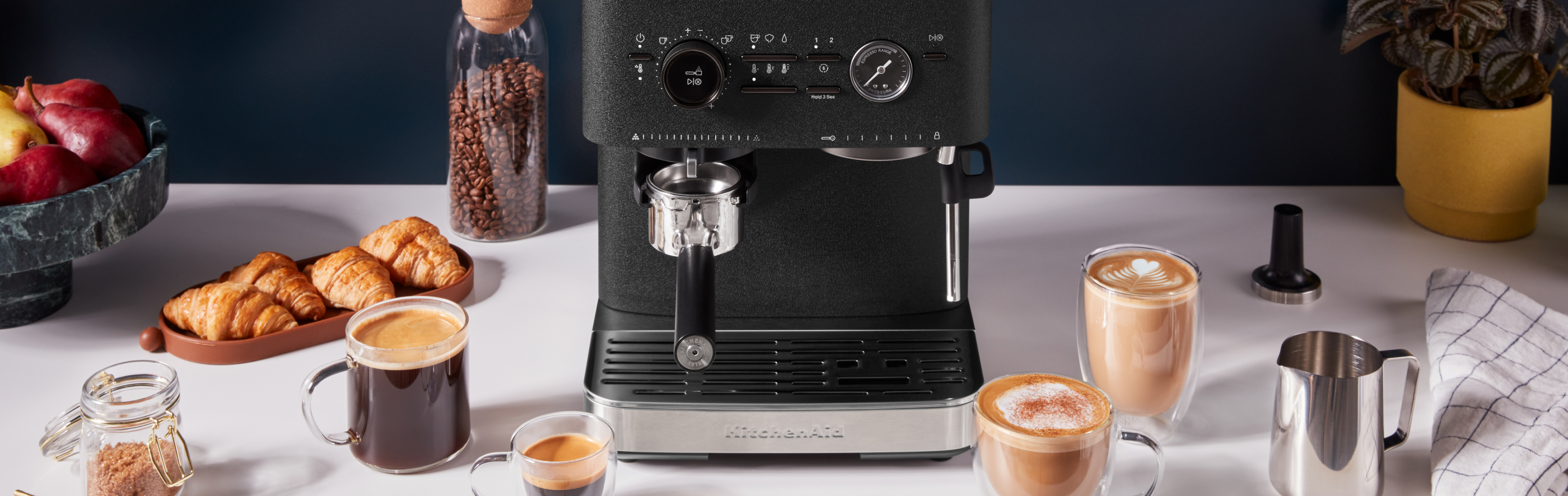 KitchenAid® Semi Automatic Espresso Machine next to a variety of espresso beverages