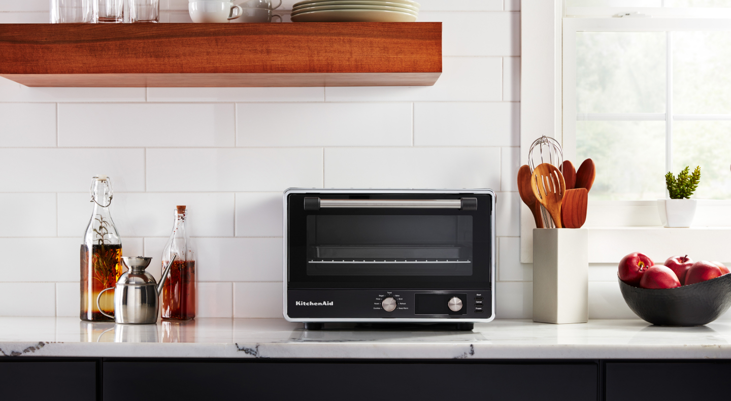 A KitchenAid® countertop oven with marinades and apples nearby. A KitchenAid® countertop oven with marinades and apples nearby.