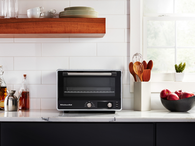 A KitchenAid® countertop oven with marinades and apples nearby. A KitchenAid® countertop oven with marinades and apples nearby.
