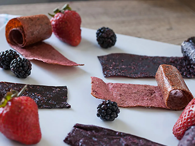 Sheets of homemade fruit leather and black berries. Sheets of homemade fruit leather and black berries.