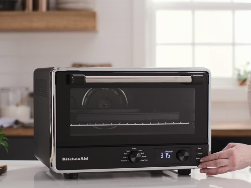 A person using a KitchenAid® countertop oven.