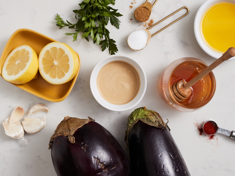 Eggplant and lemon with other baba ganoush ingredients on countertop