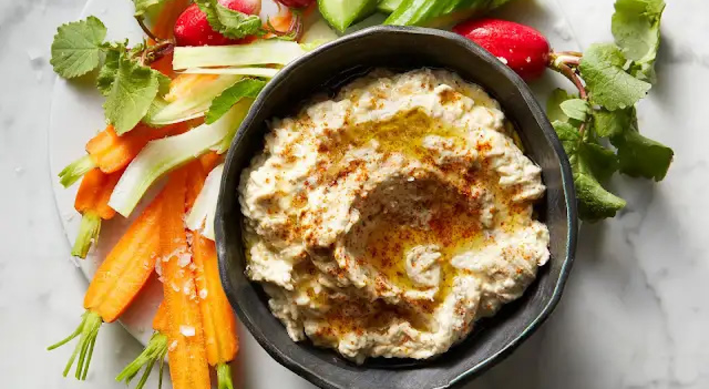 Baba ganoush in black bowl surrounded by freshly chopped carrots and radishes Baba ganoush in black bowl surrounded by freshly chopped carrots and radishes