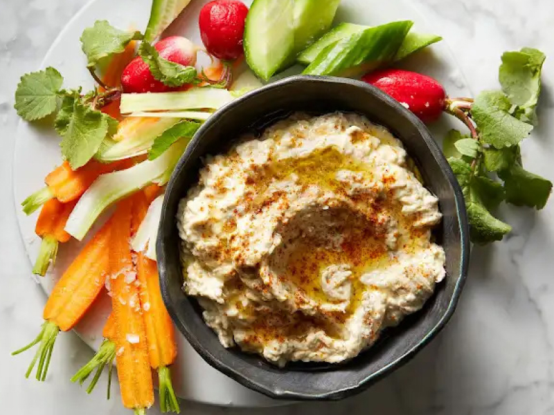 Baba ganoush in black bowl surrounded by freshly chopped carrots and radishes Baba ganoush in black bowl surrounded by freshly chopped carrots and radishes