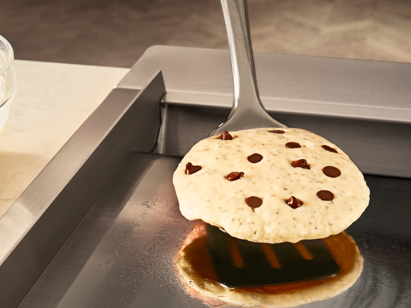 Person flipping chocolate chip pancake with spatula Person flipping chocolate chip pancake with spatula