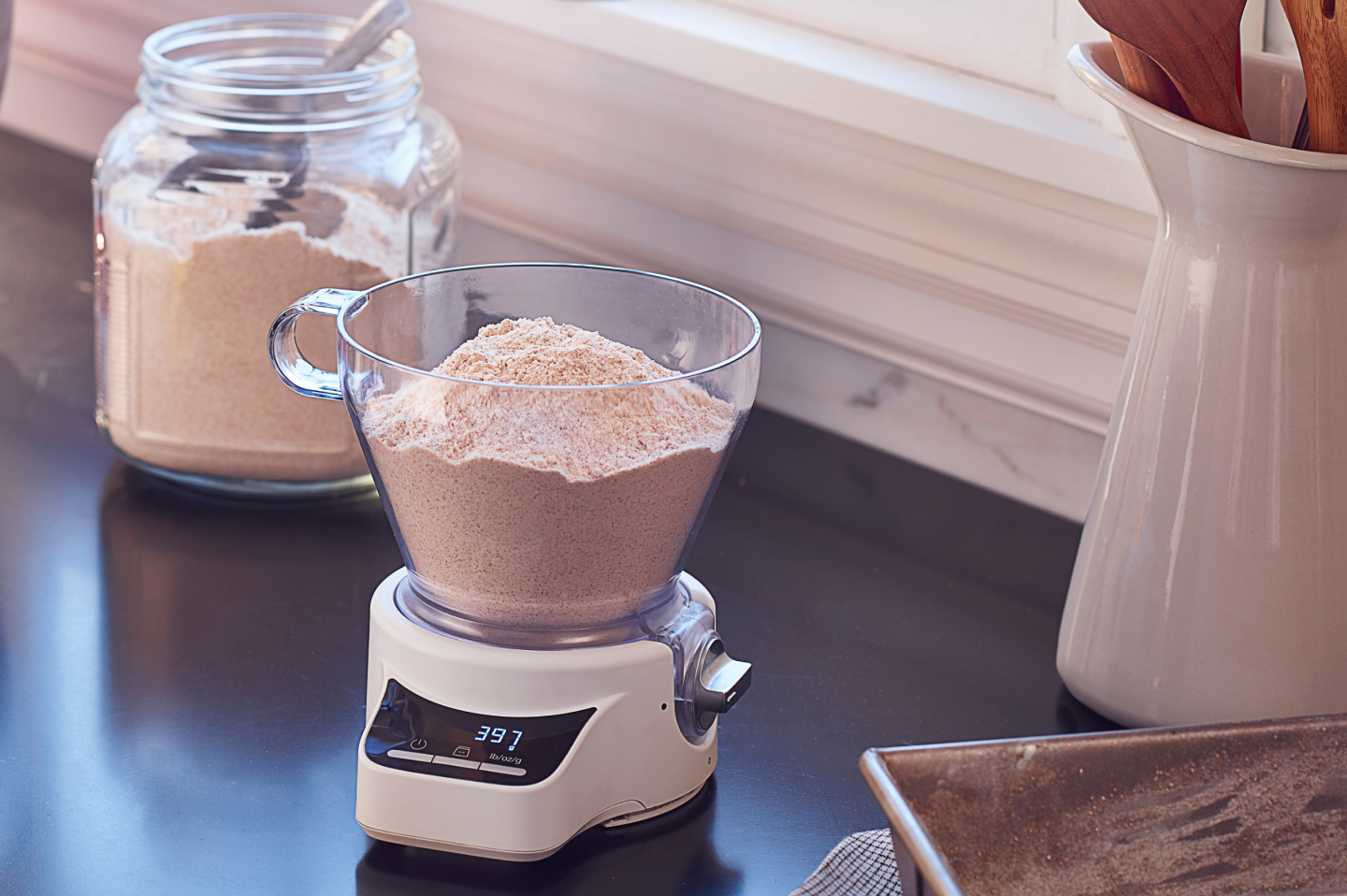 KitchenAid® Sifter + Scale Attachment sitting on countertop full of flour KitchenAid® Sifter + Scale Attachment sitting on countertop full of flour