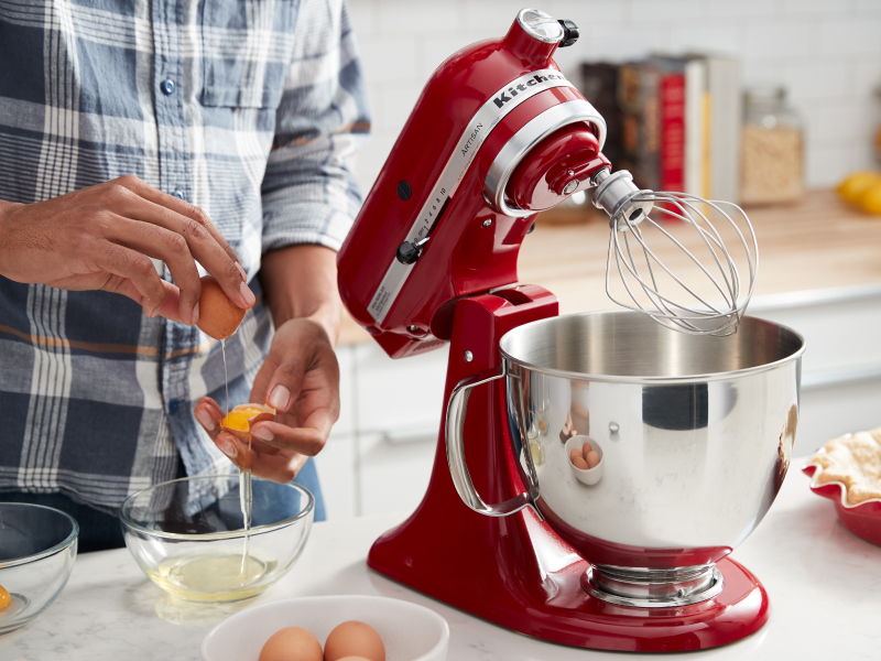 Person cracking eggs next to a KitchenAid® stand mixer with wire whip Person cracking eggs next to a KitchenAid® stand mixer with wire whip
