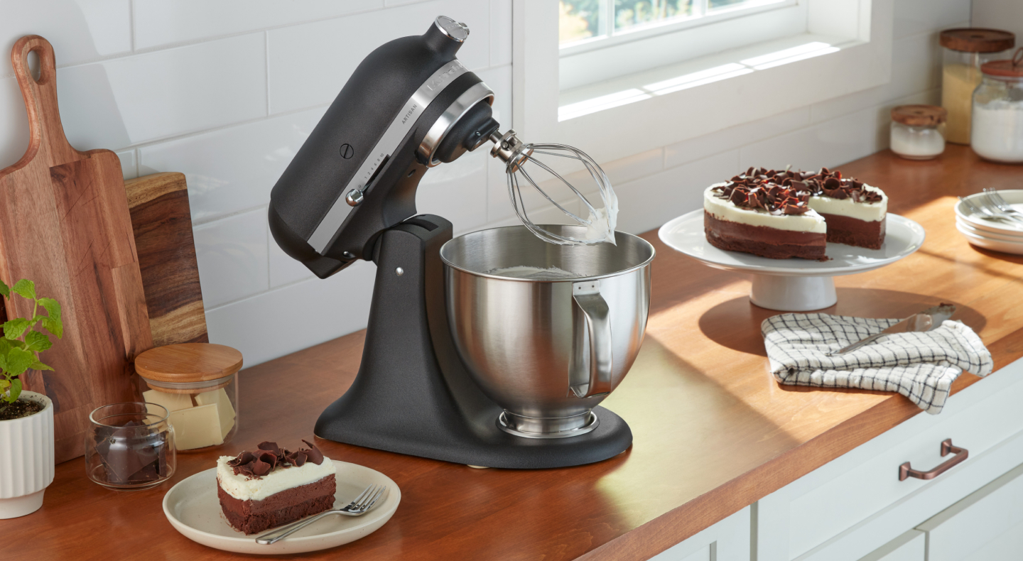 KitchenAid® stand mixer with wire whip next to cake KitchenAid® stand mixer with wire whip next to cake