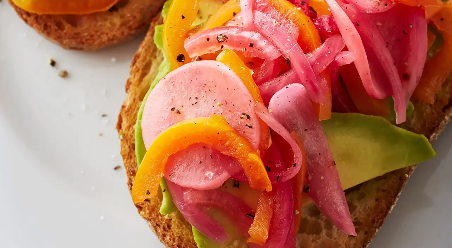 Pickled red onions on top of toast with avocado and other veggies Pickled red onions on top of toast with avocado and other veggies