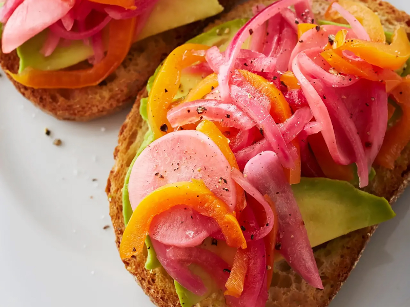 Pickled red onions on top of toast with avocado and other veggies Pickled red onions on top of toast with avocado and other veggies